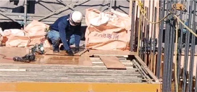 プレハブの前でポーズをとる4人の作業員