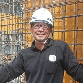 鉄筋の前で笑顔を見せる作業員